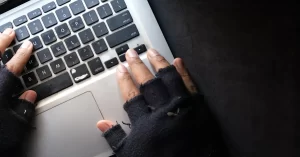 a person wearing gloves and typing on the computer